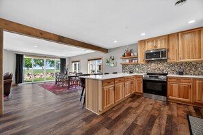 A modern kitchen with wooden cabinets, a large island, and a view to the outdoors.