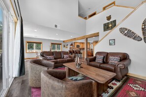 A spacious living room with leather sofas, a wooden coffee table, and a kitchen in the background.