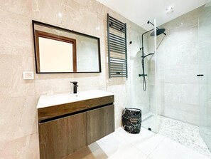 Une salle de bain moderne avec un grand miroir, un lavabo, une douche et un panier à linge.