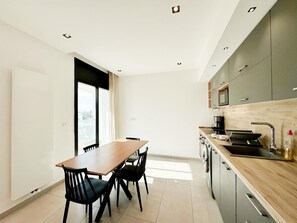 Une cuisine moderne avec une table et des chaises en bois, un four encastré et une grande fenêtre.