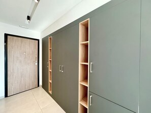 Ein Korridor mit einer Holztür, einem grauen Schrank mit mehreren Fächern und einem gefliesten Boden.