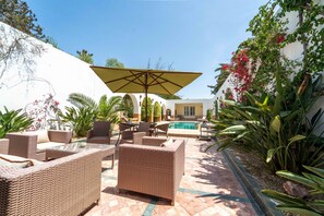 An outdoor patio with wicker furniture, a pool, and tropical plants. - Palm Paradise | 3BR Villa · Pool · La Soukra (La Soukra)