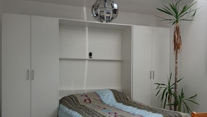Una camera da letto con un letto, una pianta sospesa, una lampada a soffitto e vista sul cielo.