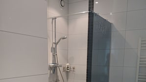 Un bagno con doccia, un lavandino bianco e un portascopevoli.