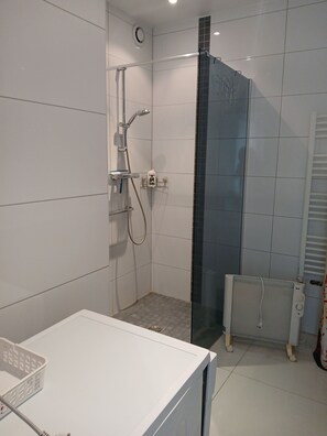 Une salle de bain avec une douche, un lavabo blanc et un porte-serviettes.