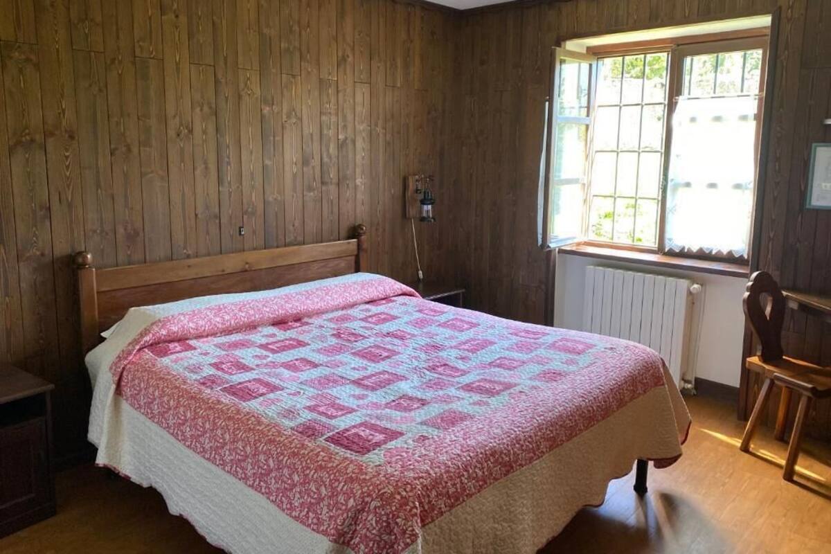 Una habitación con paneles de madera, una cama, un ventanal y un radiador.