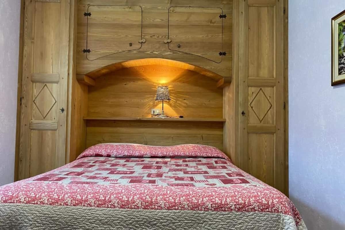 Un dormitorio con cabecera de madera, colcha estampada y una lámpara en la cabecera.
