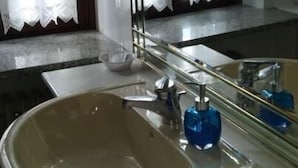 A bathroom with a sink, mirror, and window with curtains.