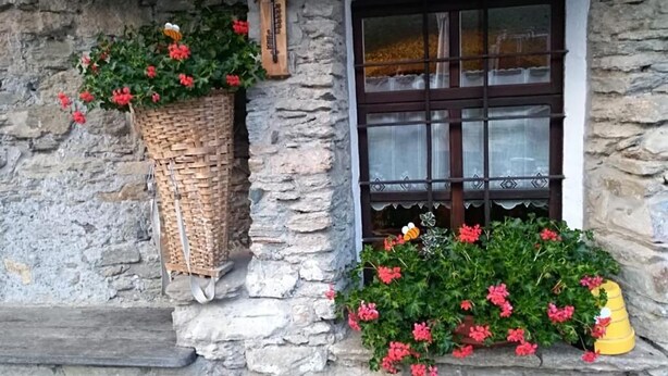 A stone building with a window, a basket with flowers, and a yellow object on the ledge.
