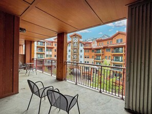 Ein Balkon mit Stühlen und Blick auf mehrstöckige Gebäude, ferner ein klarer Himmel.