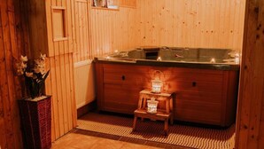Una sauna in legno con una panchetta di legno, un tavolino con candele e un termosifone.