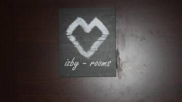 A dark wooden surface with a white heart-shaped stencil and the text 'izby - rooms' below it.