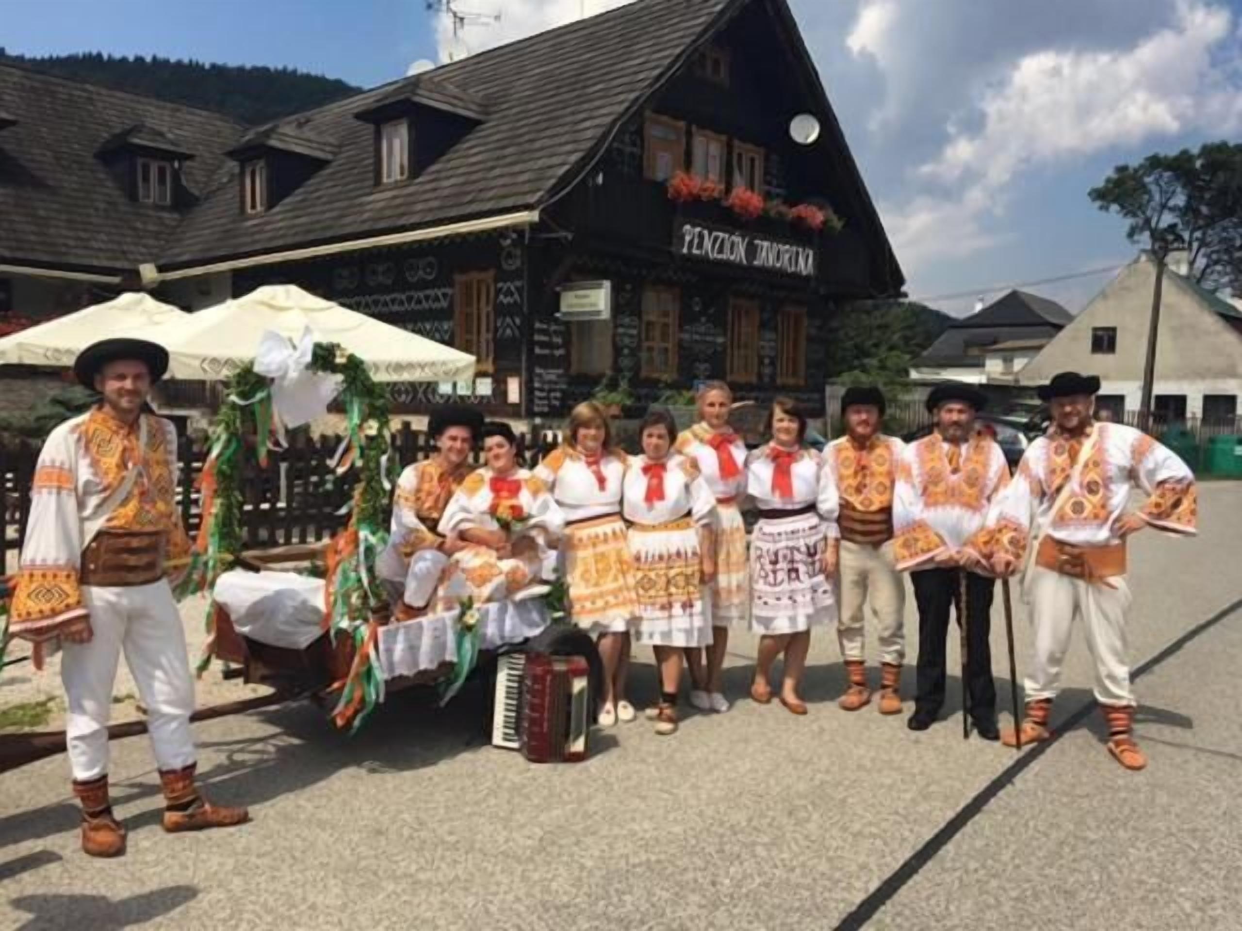 A group of people in traditional attire standing in front of a building with a sign that reads 'PENZIGEN JUNGFRIN'.