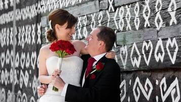A couple embracing in front of a wall with heart patterns.