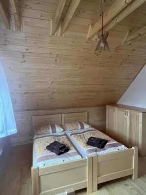 Puinen kerrossänky, jossa on pääty, pieni kaappi ja riippuvalaisin.