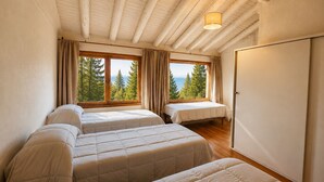 Ein Zimmer mit zwei Betten, einem Fenster mit Blick auf Bäume und einer Holzzieldecke.
