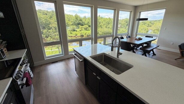 Una cocina moderna con ventanas amplias, un comedor y vistas a un bosque.