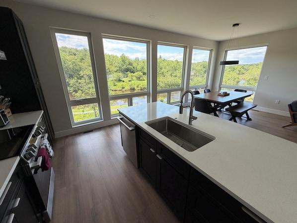 Una cocina moderna con ventanas amplias, un comedor y vistas a un bosque.