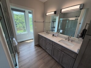 Un baño moderno con dos lavamanos, un espejo grande y vistas a zonas verdes.