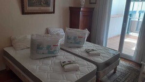 Ein Hotelzimmer mit zwei Betten, einem Bild an der Wand, einem Holzschrank und Blick durch eine Glastür.
