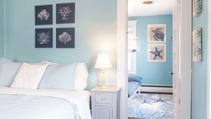 Une chambre à coucher avec un lit, une table de chevet, une lampe et des œuvres d’art murales.
