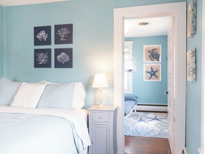 Ein Schlafzimmer mit einem Bett, einem Nachttisch, einer Lampe und Wandbildern.
