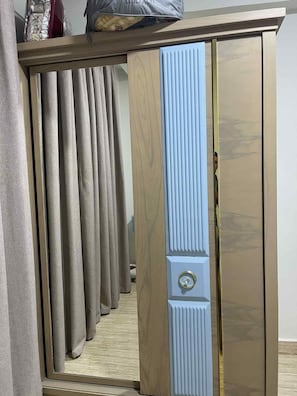 A room with a wooden wardrobe, a mirror, and a window with curtains. - sheikh zayed mini villa (Sheikh zayed city)