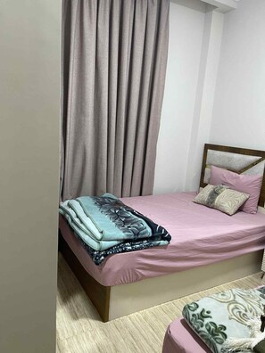A bedroom with a bed, a bedside table, a chair, and a curtain.