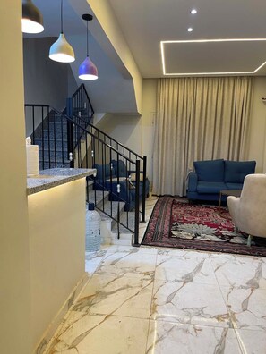 Ein modernes Wohnzimmer mit Treppe, blauem Sofa und einem gemusterten Teppich.