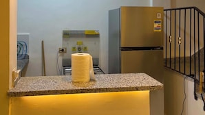 A kitchen with a central island, three pendant lights, a refrigerator, and a gas stove.