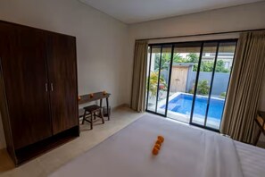 Habitación de hotel con cama, escritorio, armario y vistas a una piscina.