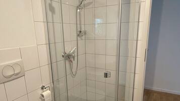 A bathroom with a glass-enclosed shower, a toilet, and a sink.