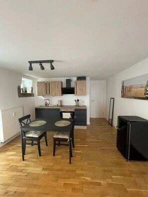 Een moderne keuken met houten kastjes, een eettafel met stoelen en een zwart apparaat.