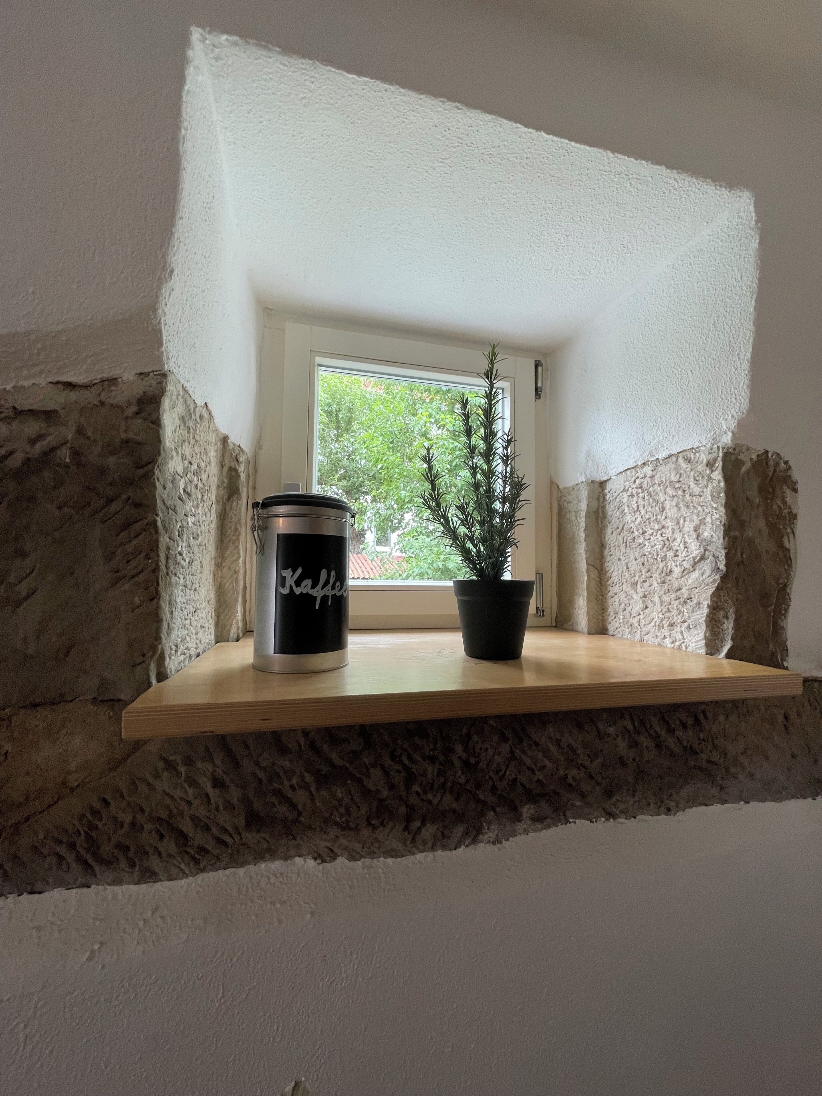 A shelf with a black container labeled 'Kaffee' and a potted plant.