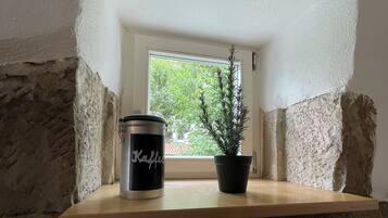 A shelf with a black container labeled 'Kaffee' and a potted plant.