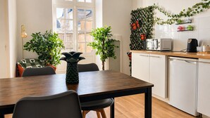 A modern kitchen with a dining area, white cabinets, and a window with a view of buildings. - Cosy apartment in the heart of Angers historic district – Terrace & comfort – Sleeps 2 (Angers)