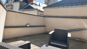 A rooftop patio with outdoor furniture, a potted plant, and a view of a cathedral. - Cosy apartment in the heart of Angers historic district – Terrace & comfort – Sleeps 2 (Angers)