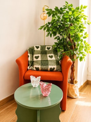 Une pièce avec une table verte, une chaise orange, une plante en pot et une lampe.