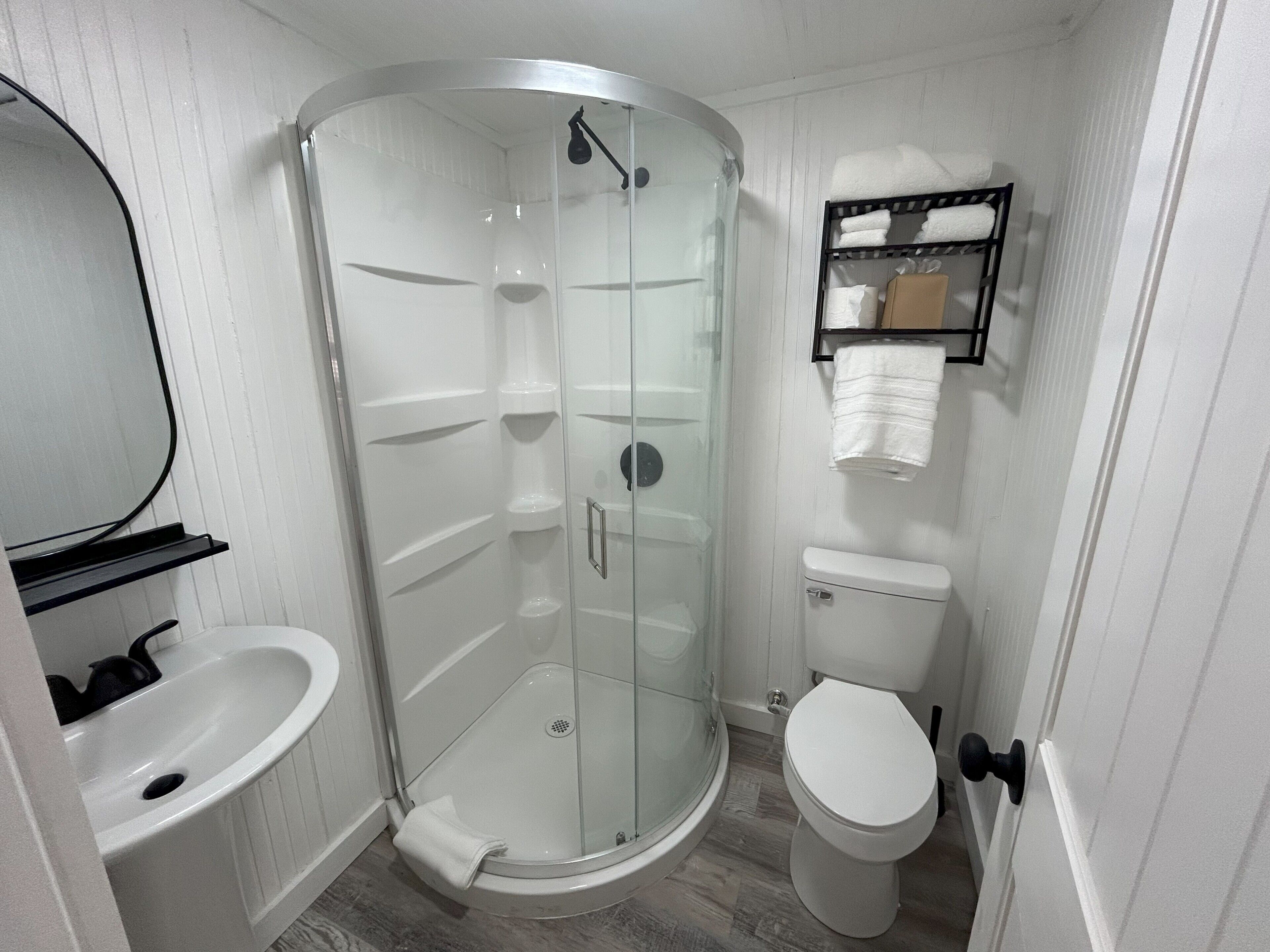 A bathroom with a glass-enclosed shower, a white toilet, and a sink.. Old Florida Fish Camp Cedar Key