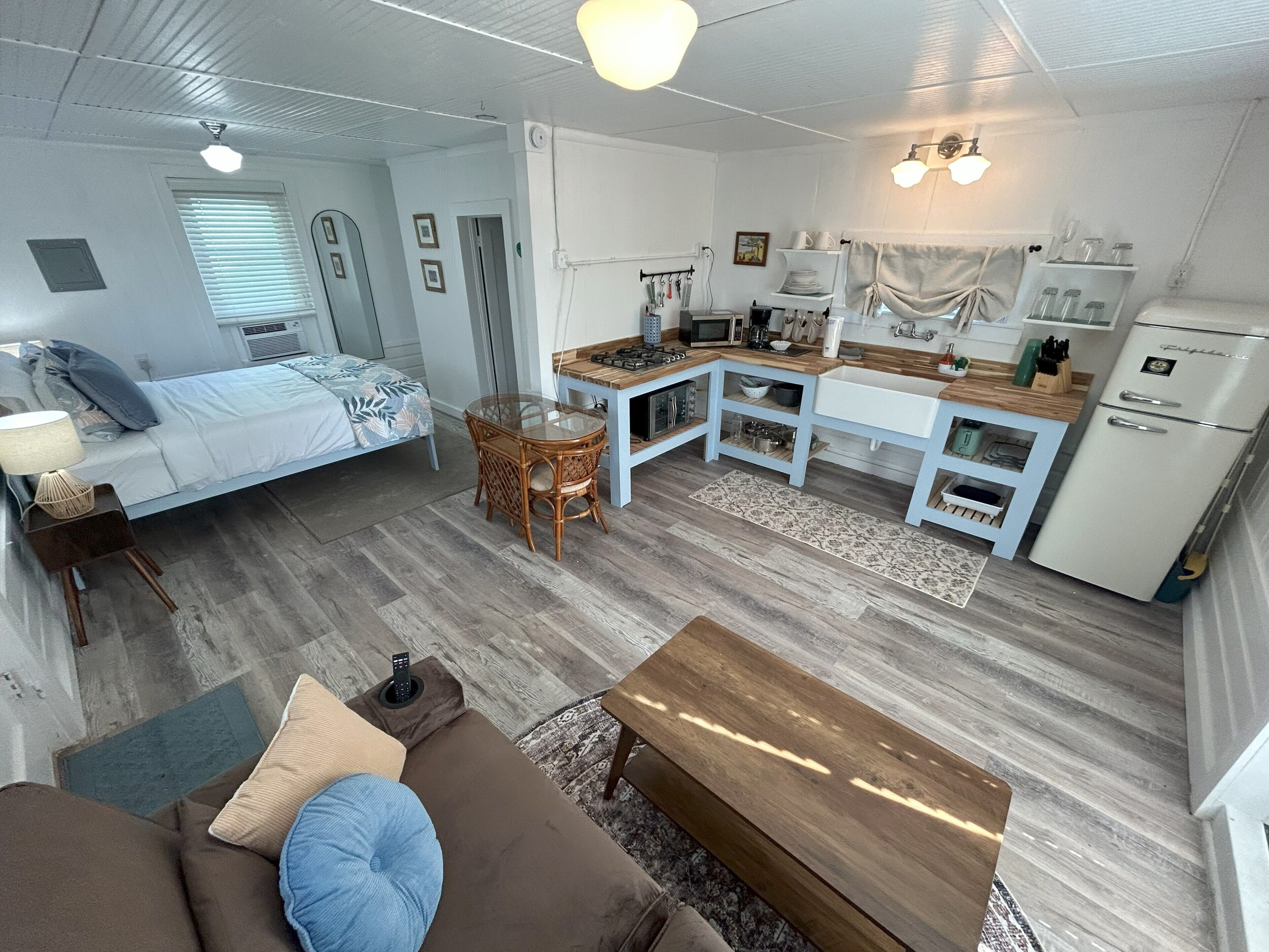 A compact living space with a bed, kitchenette, dining area, and a sofa.