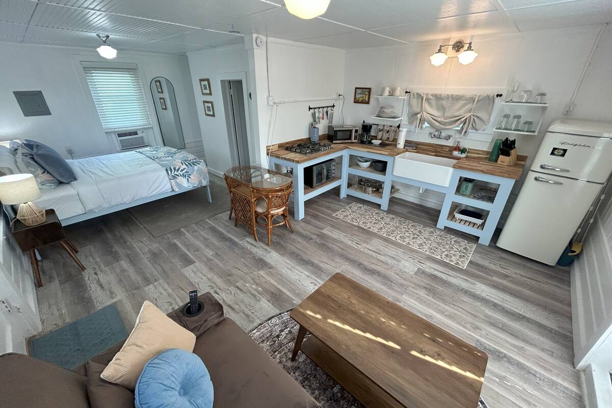 Un espacio habitable compacto con cama, kitchenette, comedor y sofá.