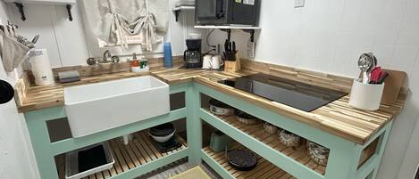 A kitchen with a sink, microwave, and various utensils.