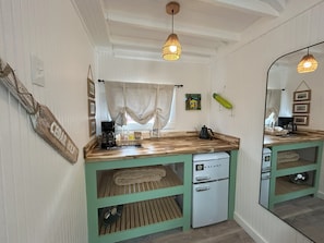 A compact kitchen with a coffee maker, kettle, and a small refrigerator.