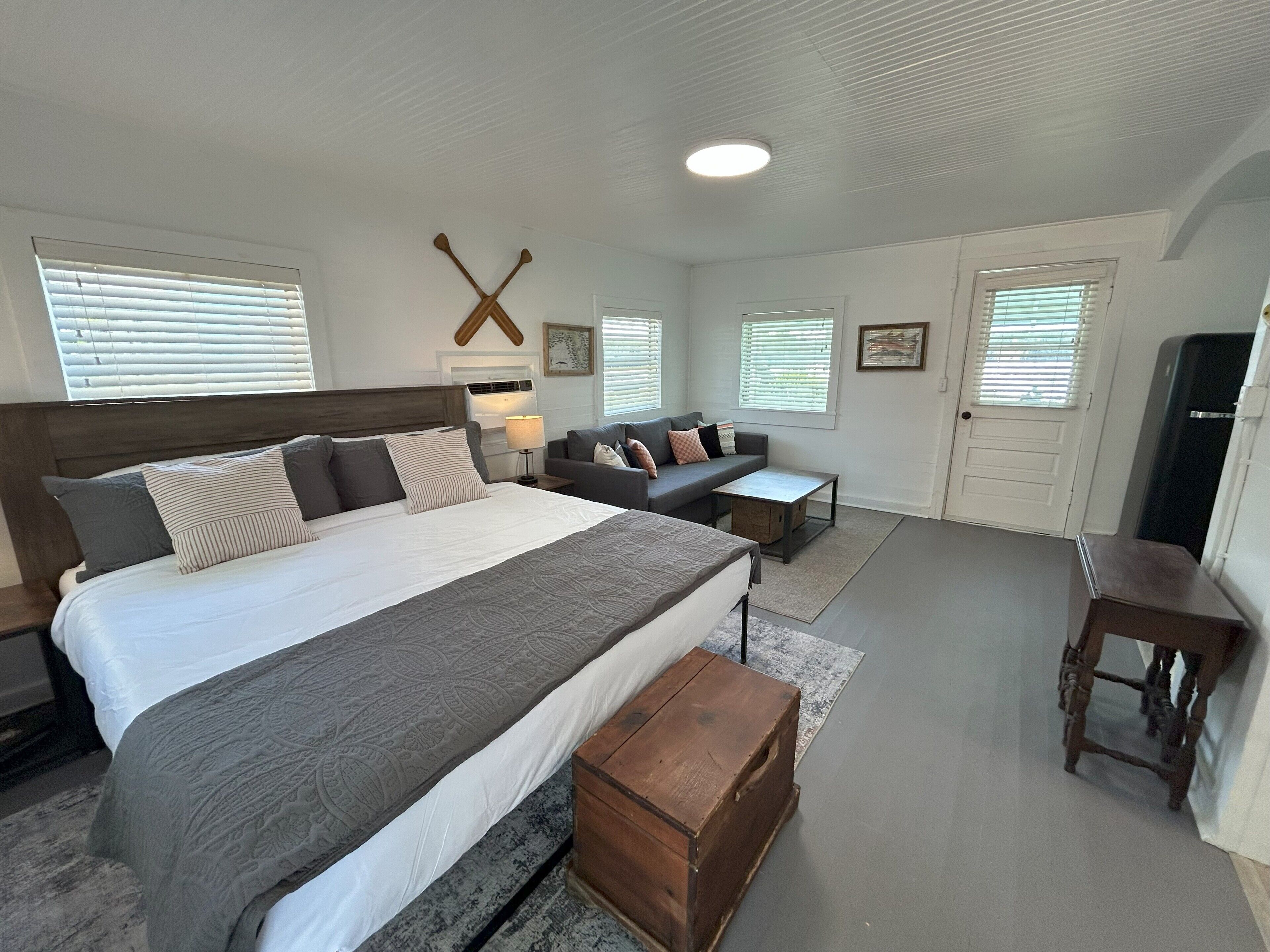 A bedroom with a large bed, a sofa, a wooden chest, and a desk.