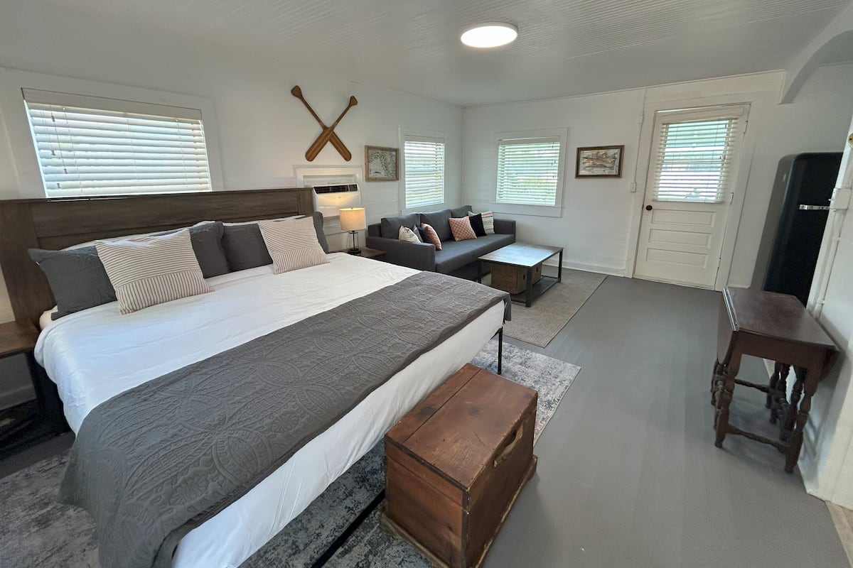 Un dormitorio con una cama grande, un sofá, un cofre de madera y un escritorio.