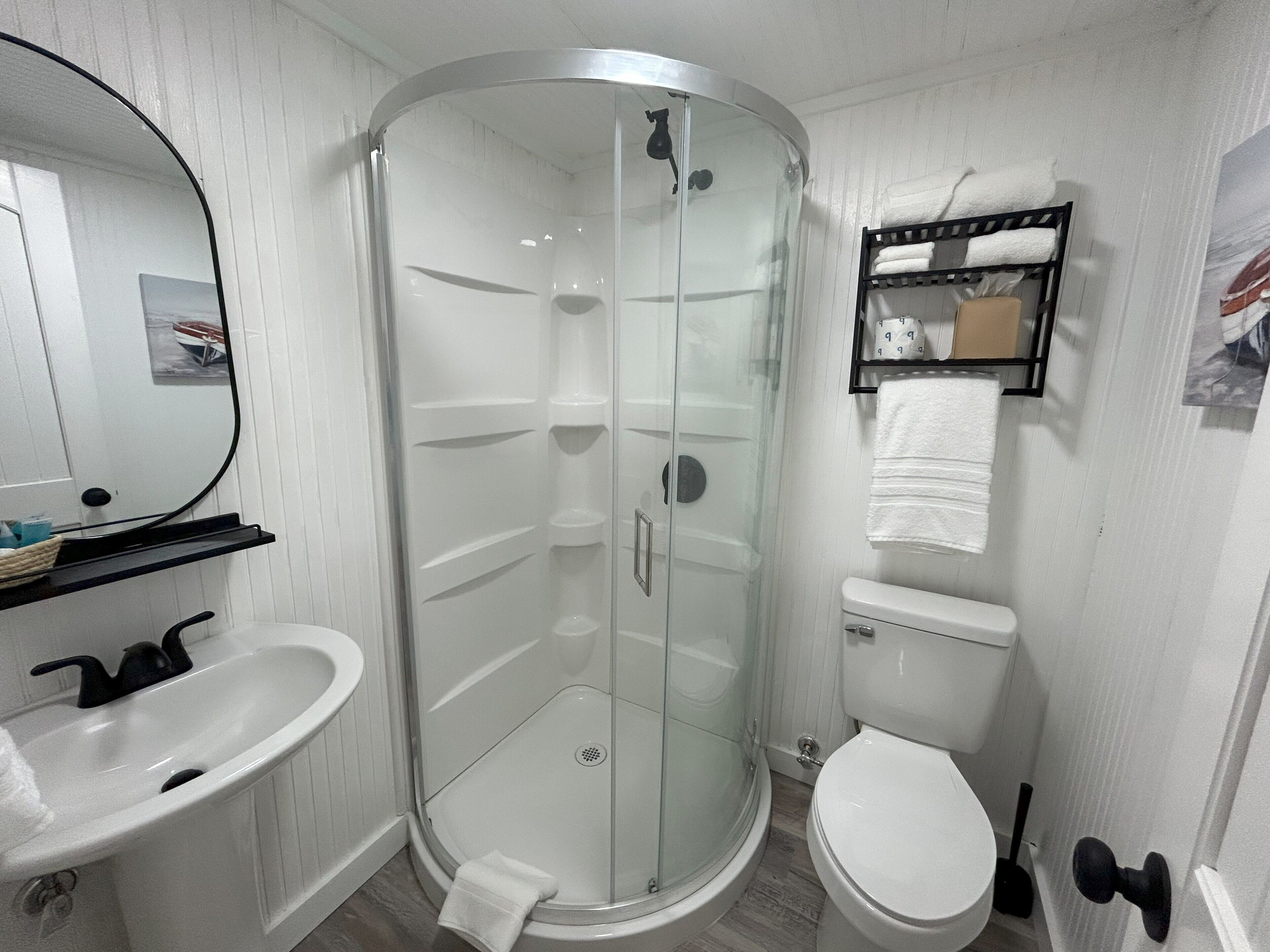 A bathroom with a glass-enclosed shower, a white sink, and a toilet.
