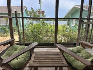 Una terraza de madera con dos bancos, una mesa y vistas a un lago y edificios.