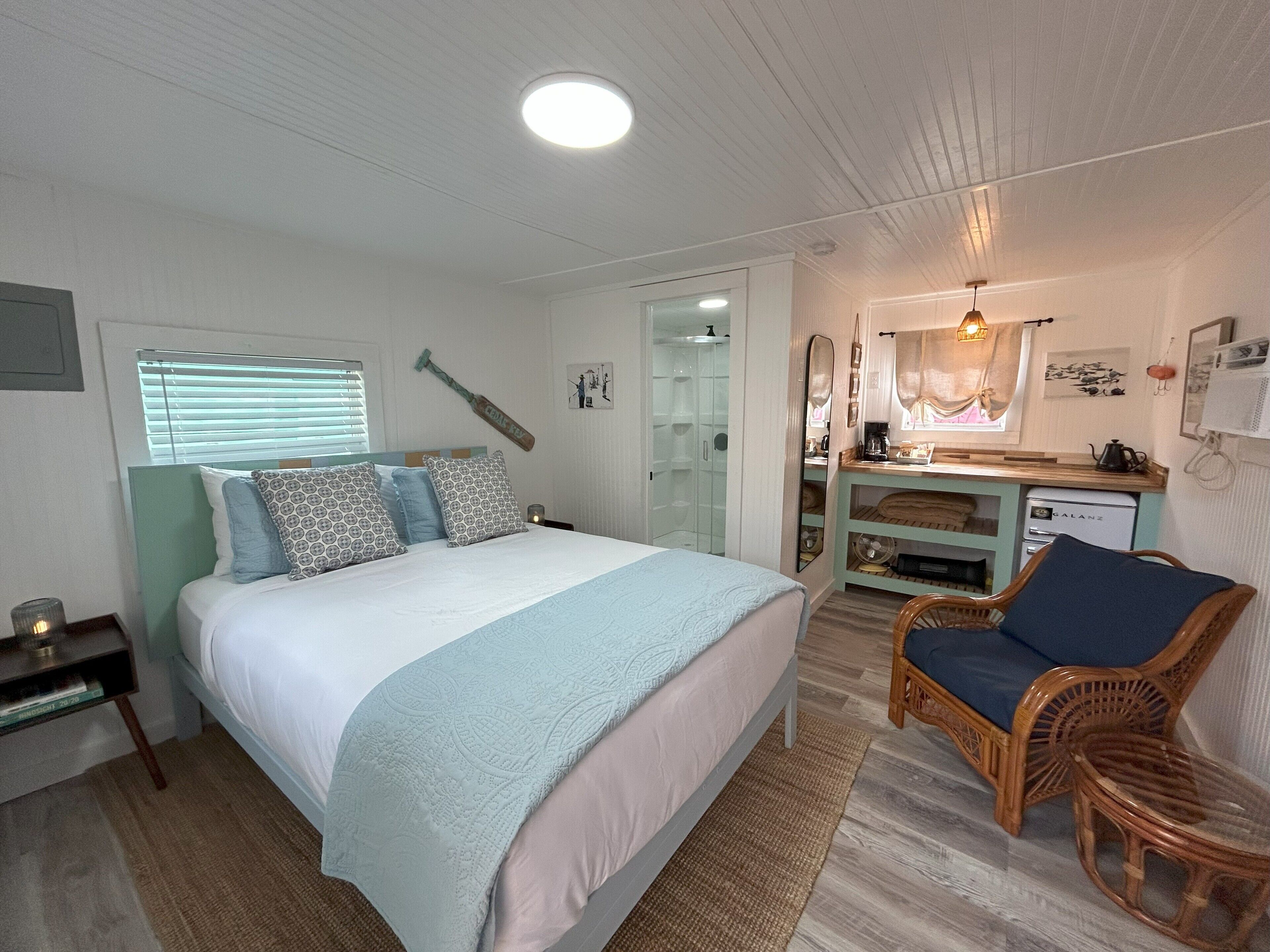 A bedroom with a bed, bedside table, chair, desk, and a walk-in closet.
