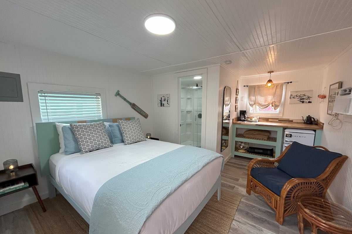 Un dormitorio con cama, mesita de noche, silla, escritorio y vestidor.