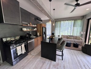 Eine moderne Küche mit Kochinsel, integrierten Geräten und einer Essecke mit Sofa und Couchtisch.